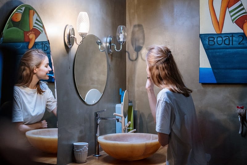 female brushing teeth in mirror image
